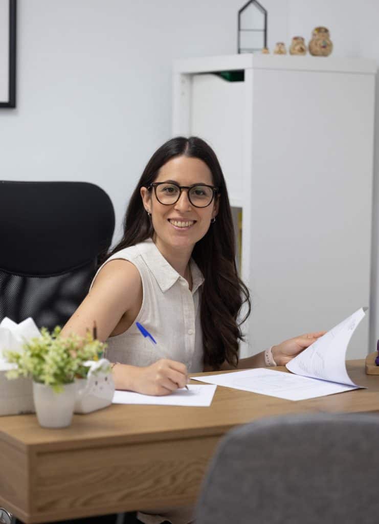 Una mujer con gafas sentada en un escritorio en una oficina.